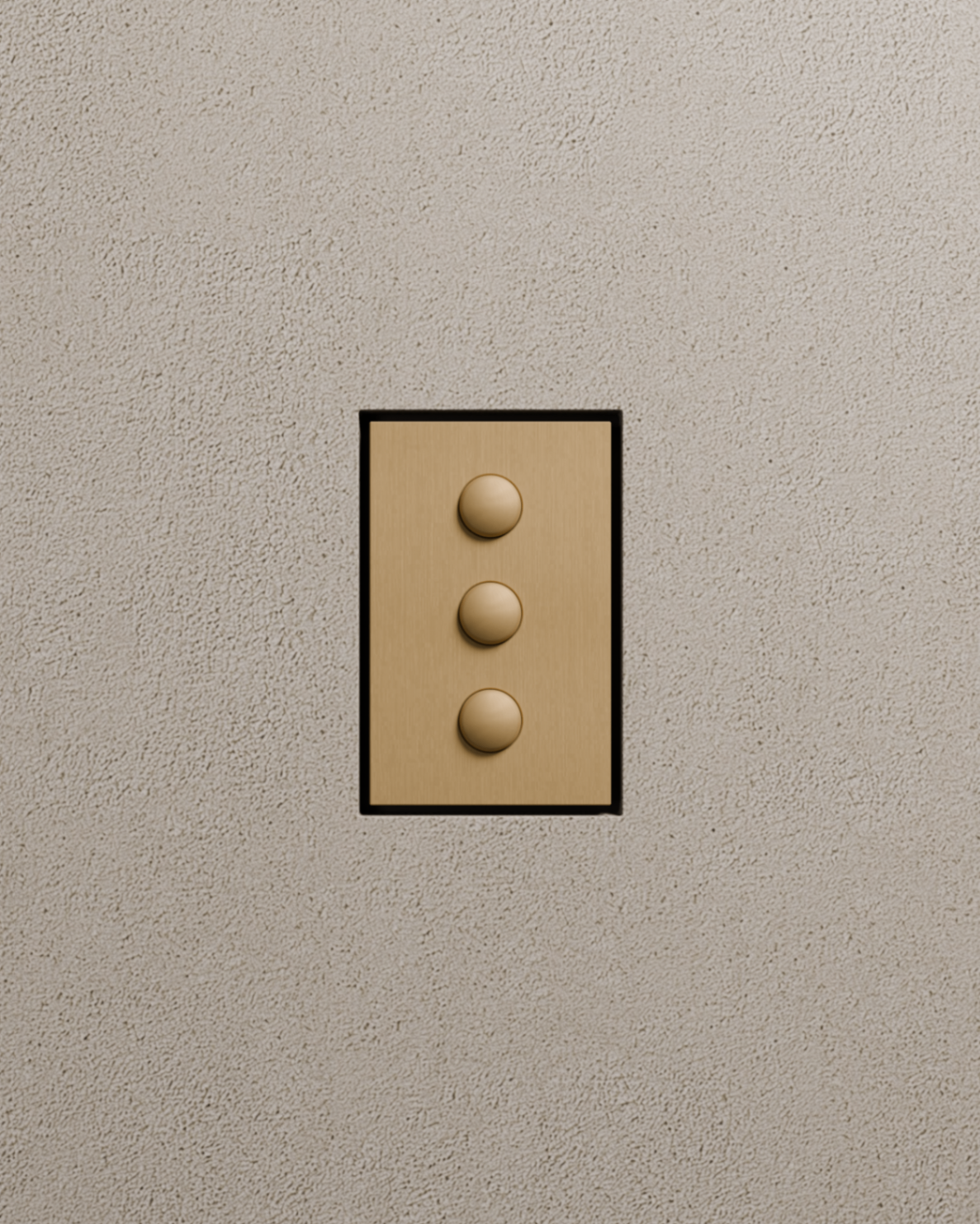 Three push-button switches in brushed brass finish on a textured plaster wall