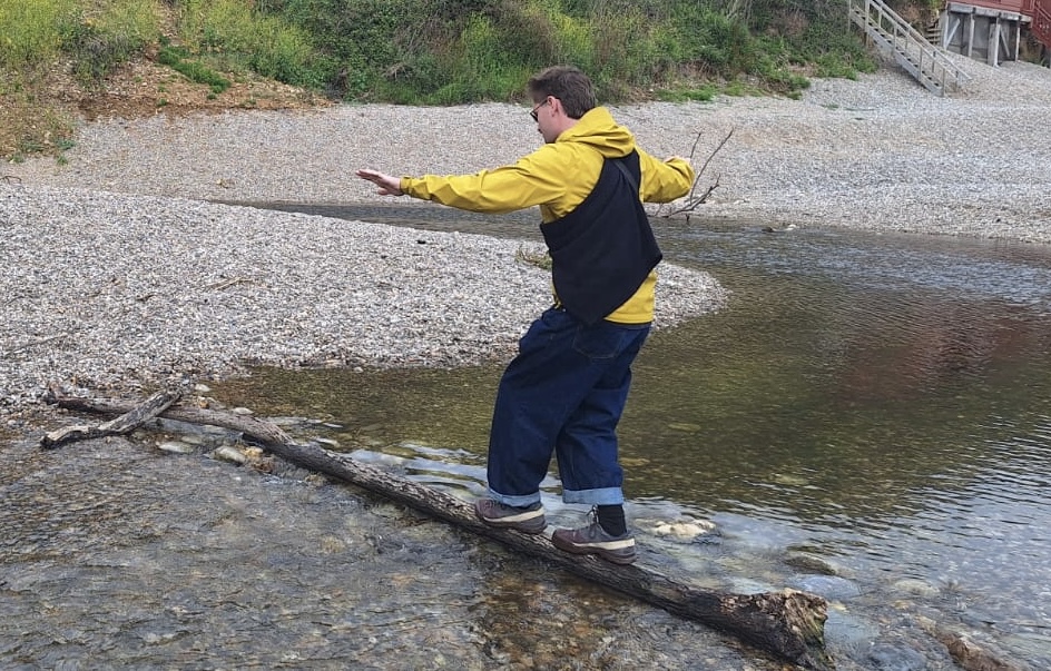 Benjamin Panis balancing on a log across a stream
